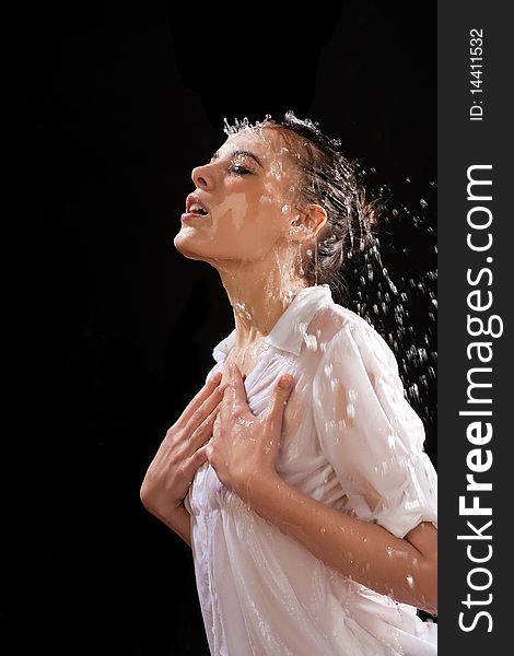 The girl in a white blouse with water splashes on a black background. The girl in a white blouse with water splashes on a black background