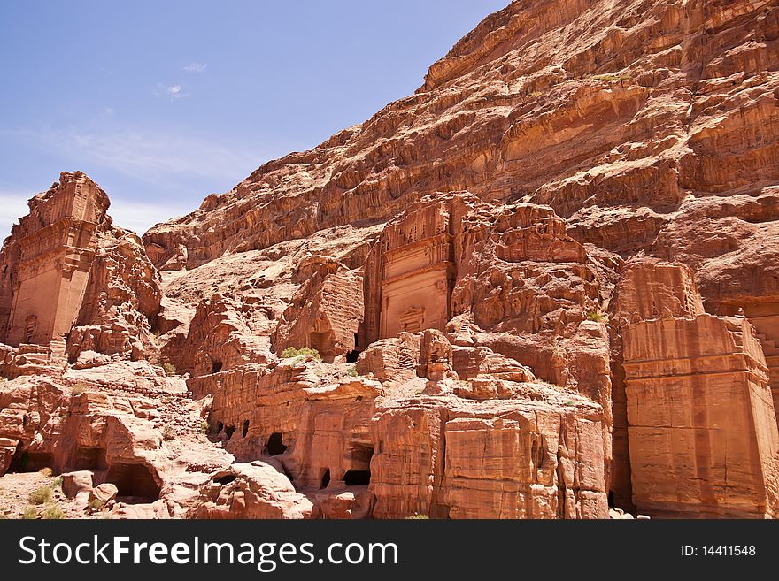 The view of large cliff side tomb carved from the beautiful richly-colored sandstone in the ancient city of Petra, Jordan. The view of large cliff side tomb carved from the beautiful richly-colored sandstone in the ancient city of Petra, Jordan