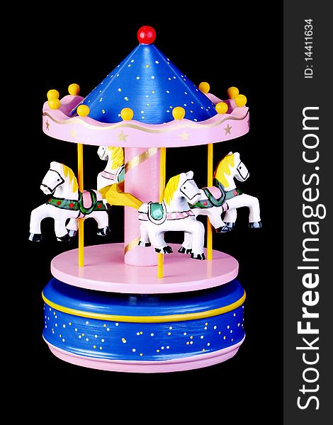 A vintage colorful wooden roundabout toy with horses, on isolated black background