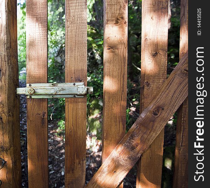 A wooden gate with a metal lever closure. A wooden gate with a metal lever closure