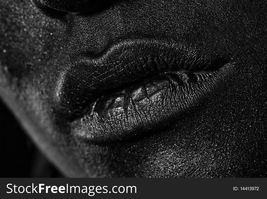 The lips of a young girl covered with black paint