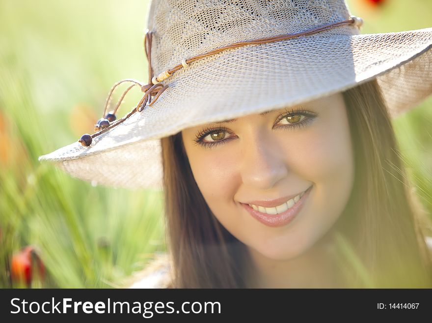 Young beautiful girl with hat staring at camera among green wheat. Young beautiful girl with hat staring at camera among green wheat.