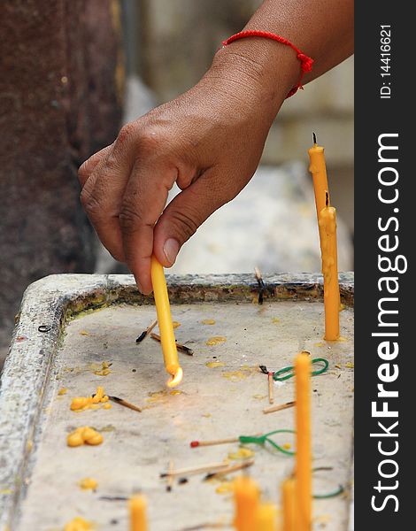 Woman in a temple lighting one candle with another candle. Woman in a temple lighting one candle with another candle