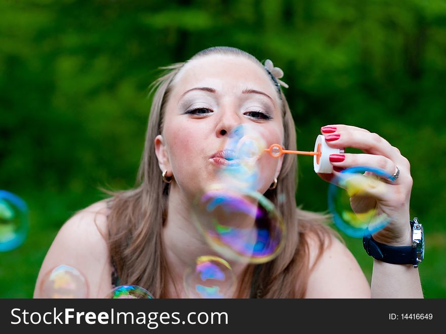 Yang woman making bubbles. Outdoor shot. In park