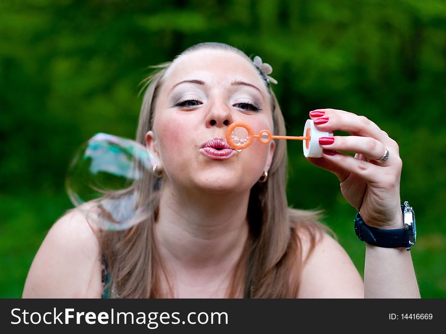 Yang woman making bubbles. Outdoor shot. In park