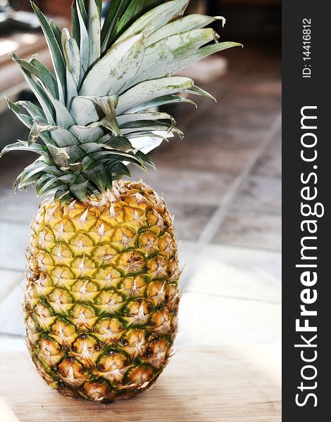 A whole, fresh pineapple sitting on a cutting board.