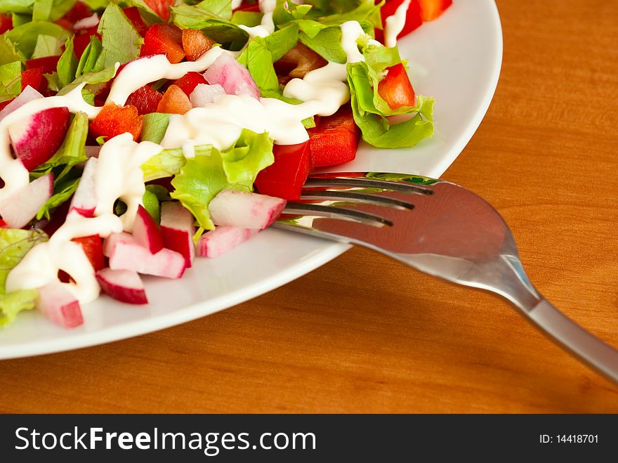 Depicted in white salad bowl, fork, close-up