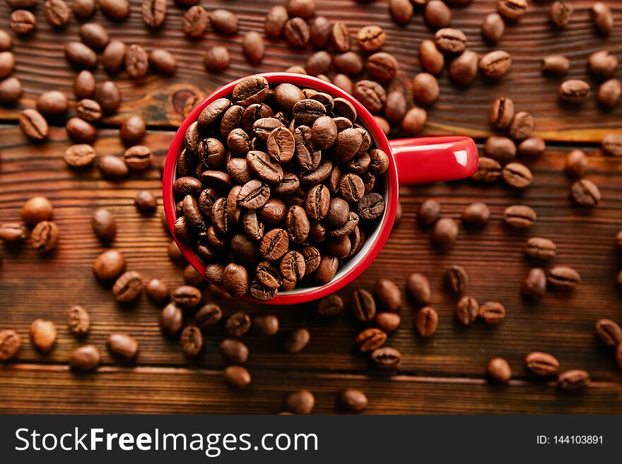 Coffee cup with roasted brown beans scattered on white table with a lot copy space for text. Flat lay composition. Close up, top view, background. Coffee cup with roasted brown beans scattered on white table with a lot copy space for text. Flat lay composition. Close up, top view, background