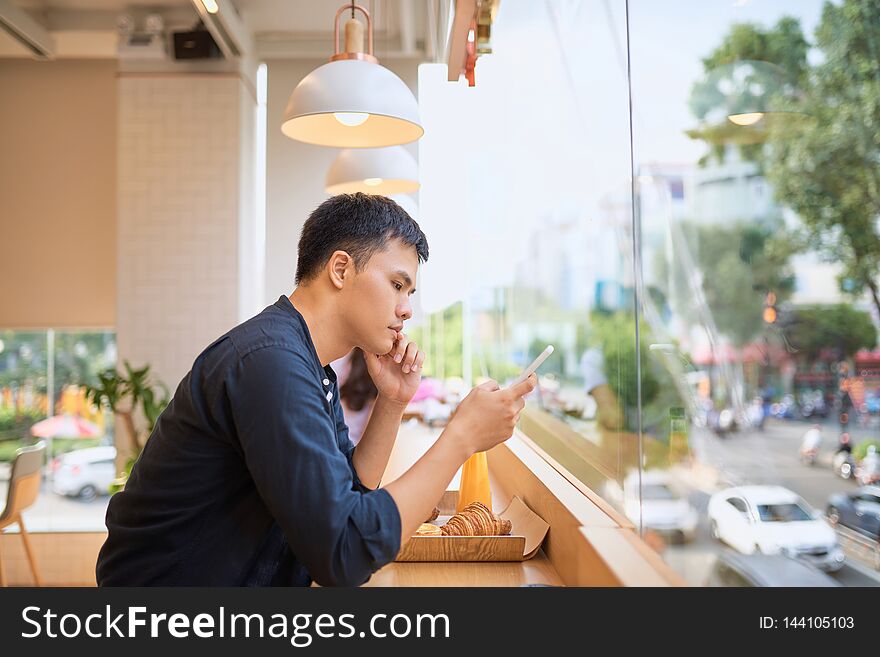 Male using smart phone while sits at terrace cafe