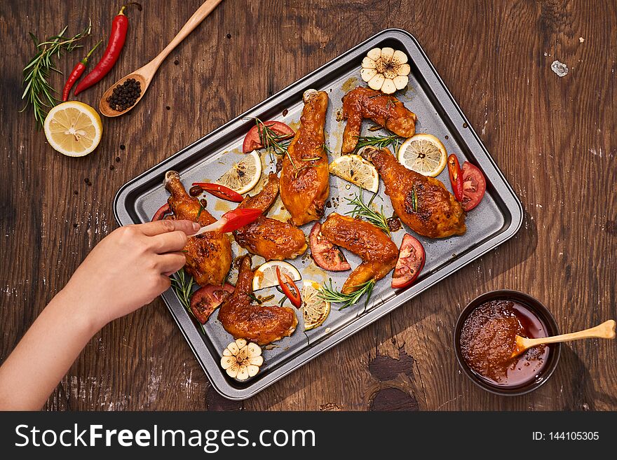 Grilled chicken drumstick and wings on baking tray over wooden table