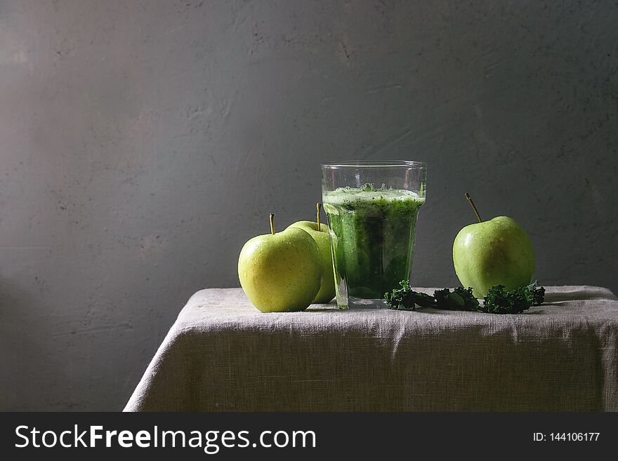 Green spinach kale apple smoothie in glass on linen table cloth with ingredients above. Healthy organic eating. Green spinach kale apple smoothie in glass on linen table cloth with ingredients above. Healthy organic eating.