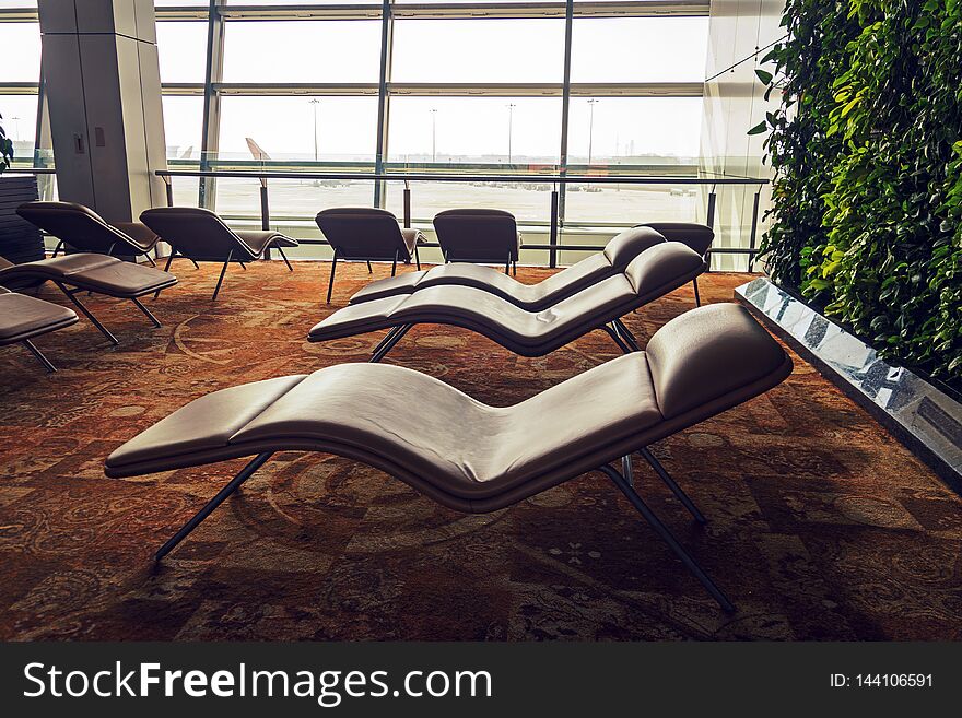 soft comfortable sunbeds in the airport waiting room in front of the panoramic window