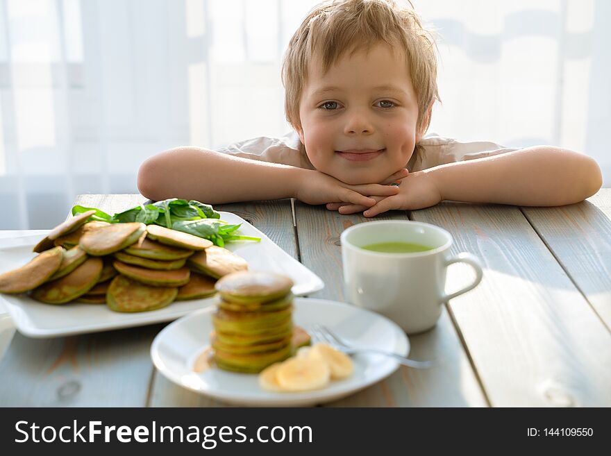 Cute five year boy with stack of spinach pancakes