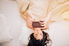 Beautiful Young Smiling Brunette Woman Using Phone In Her Bedroom Royalty Free Stock Image