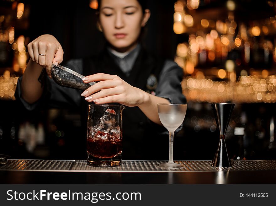 Bartender girl adding ice from the metal paddle