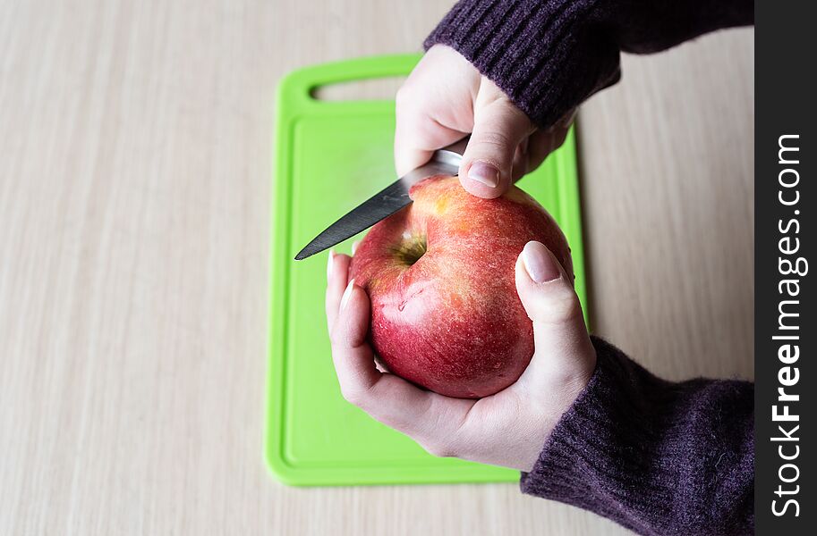 Girl cleans the apple with a knife. Healthy food. Close up