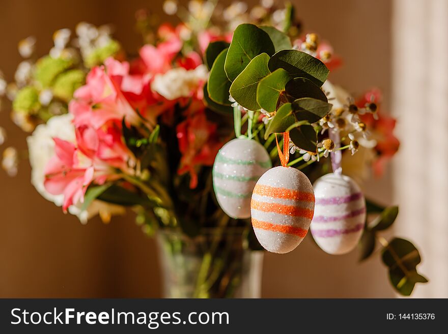 Lush bouquet with berries and daisies and Easter eggs in sequins hang on it in sunlight close-up shallow depth of field. Lush bouquet with berries and daisies and Easter eggs in sequins hang on it in sunlight close-up shallow depth of field