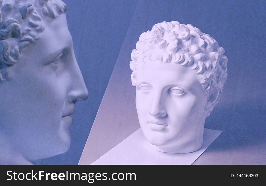 Plaster head sculpture, bust portrait of a young man, classical sculpture for academic drawing, dark background. Selected focus.