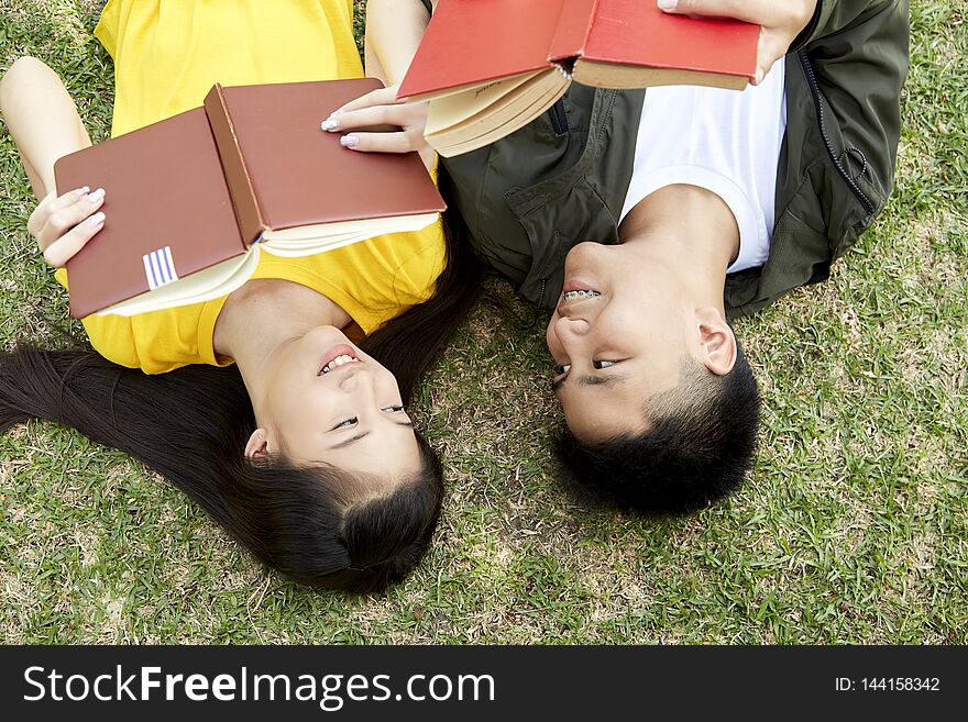 Back to school, Teenagers asian boy and girl happy students with books lying on green grass at school park, concept is happy with finding knowledge. Back to school, Teenagers asian boy and girl happy students with books lying on green grass at school park, concept is happy with finding knowledge