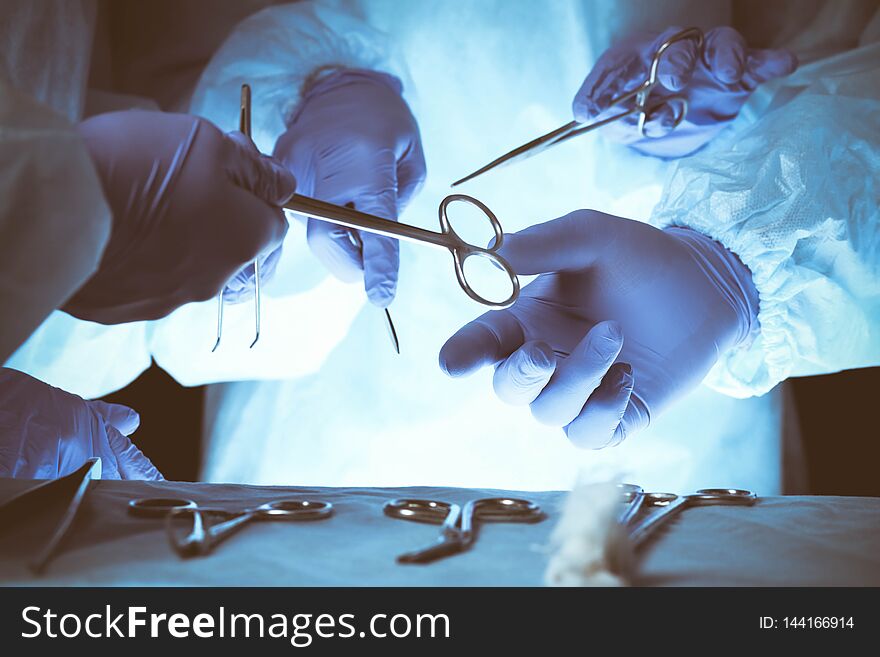 Surgeons hands holding surgical scissors and passing surgical equipment, close-up. Health care and veterinary concept.