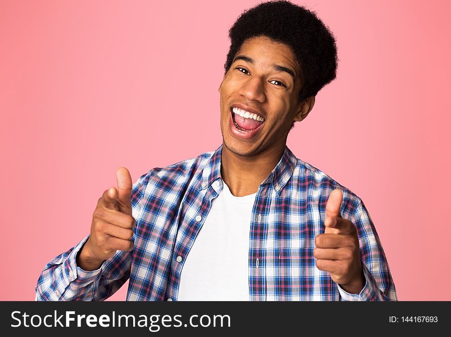 Excited guy pointing fingers at camera over pink background