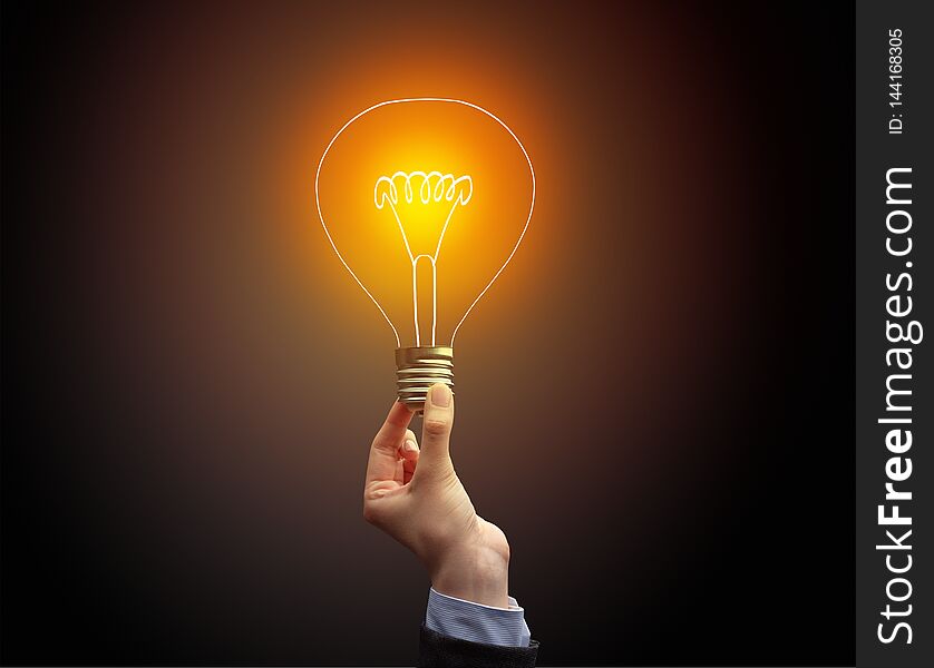 Hand holding light bulb on dark background, new idea concept