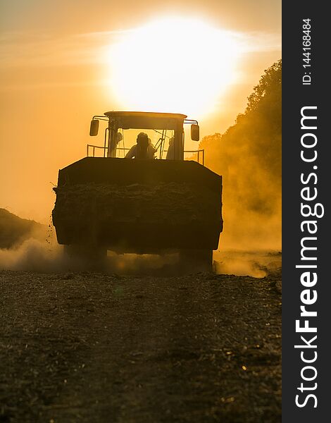 Agricultural machinery on the field at sunset, tractor in sunlight