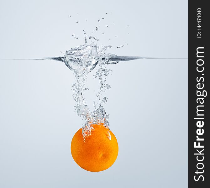 A Slice Of Red Orange Falls Into The Water Discarding A Lot Of Splashes And Drops