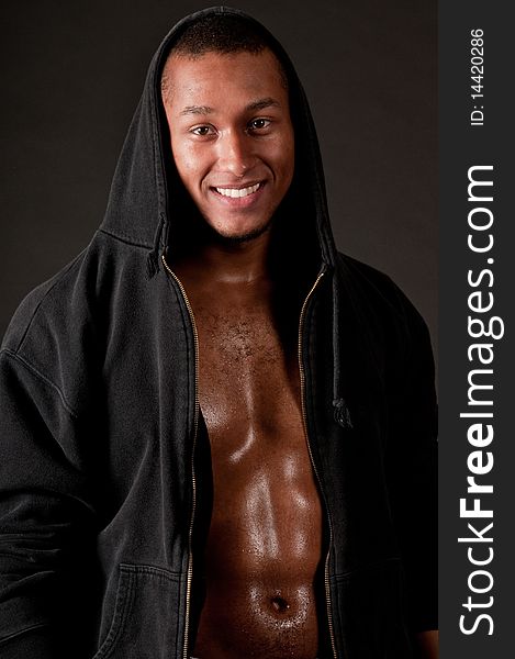 Young muscular male in hood on black background