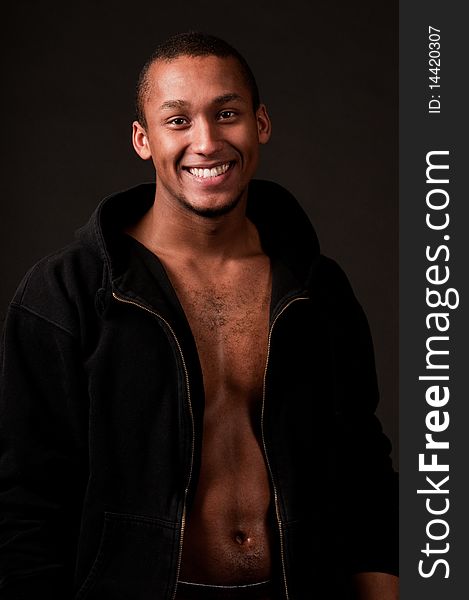 Young muscular male in hood on black background