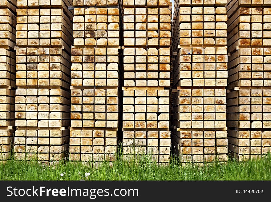 Pattern of cut wood stacks in rectangular formation with green grass in foreground. Pattern of cut wood stacks in rectangular formation with green grass in foreground.