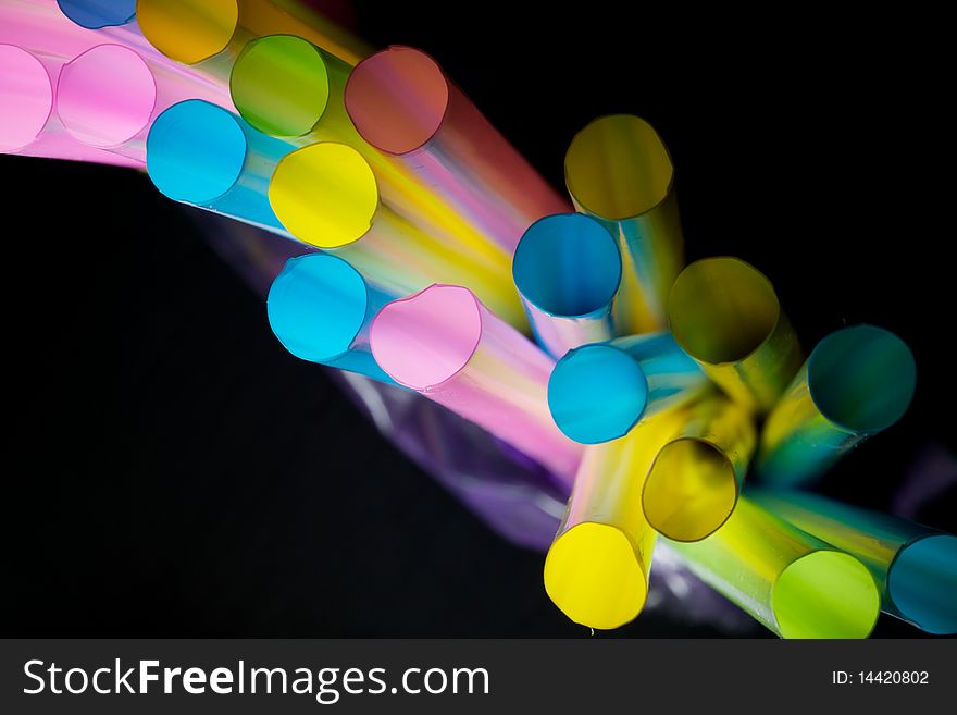 A row of colorful straws in the isolated black background. A row of colorful straws in the isolated black background.