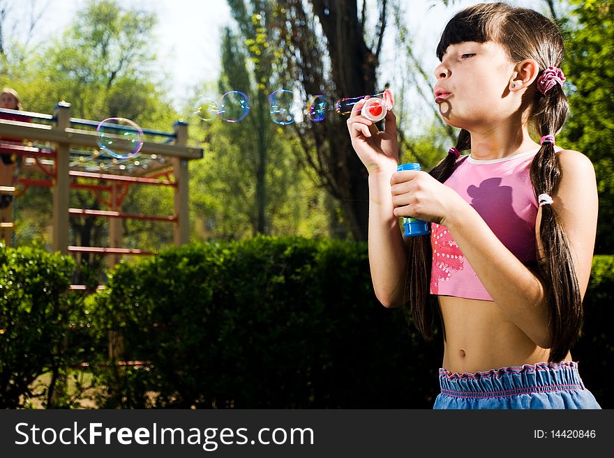 Nice girl with soap bubbles in park