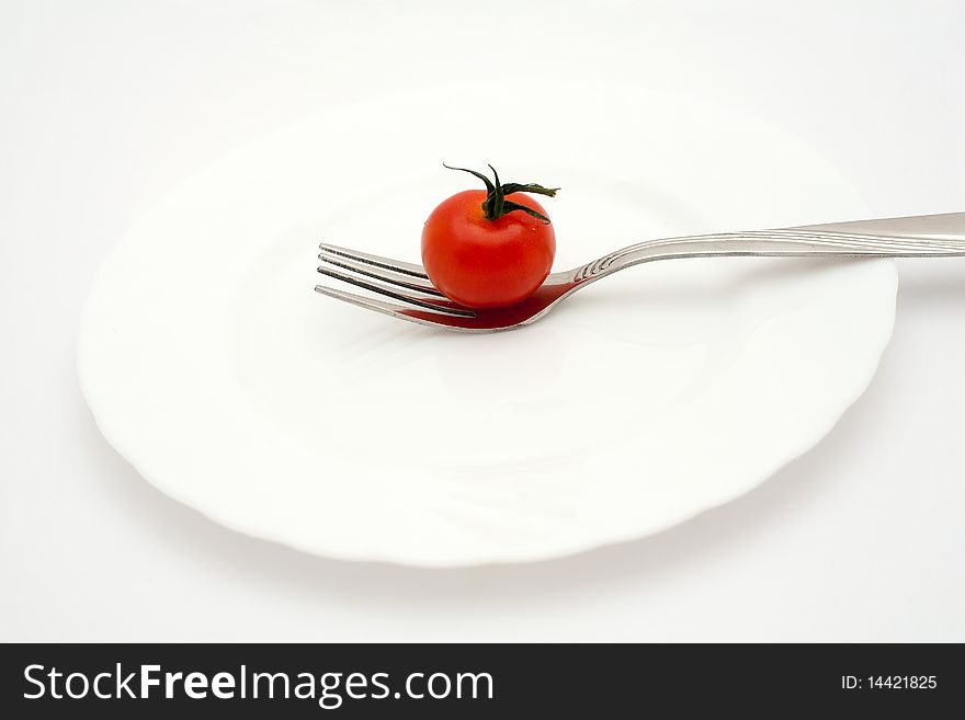 An image of a little red tomato on the fork