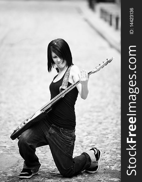 Joyful young woman playing a guitar at the street. Joyful young woman playing a guitar at the street