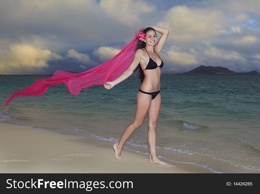 Beautiful young woman on lanikai beach at sunrise in a bikini with a long chiffon scarf