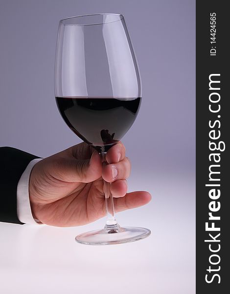 Image of glass of red wine held by a gentleman wearing a suit. Image of glass of red wine held by a gentleman wearing a suit.