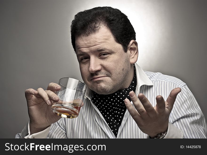 Handsome man in a shirt with a glass of cognac looking at the viewer and smiling. Handsome man in a shirt with a glass of cognac looking at the viewer and smiling.