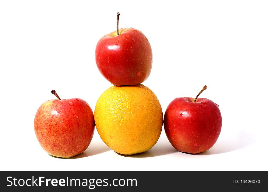 Red apples and orange in pyramid with shadow isolated over white