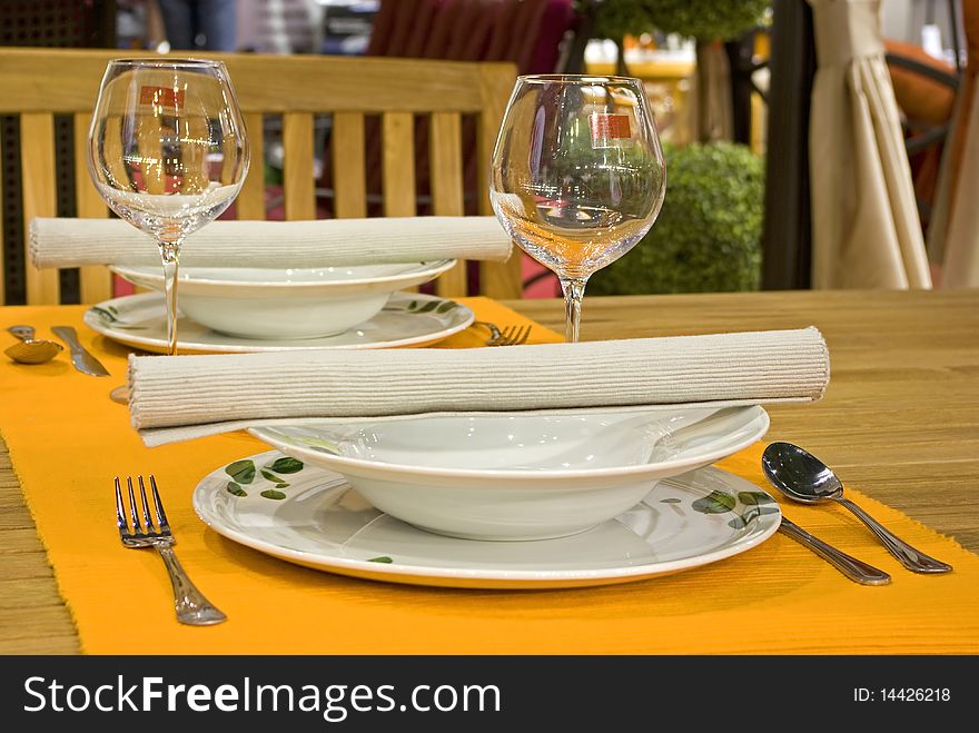White dinner set on orange doily with silver cutlery