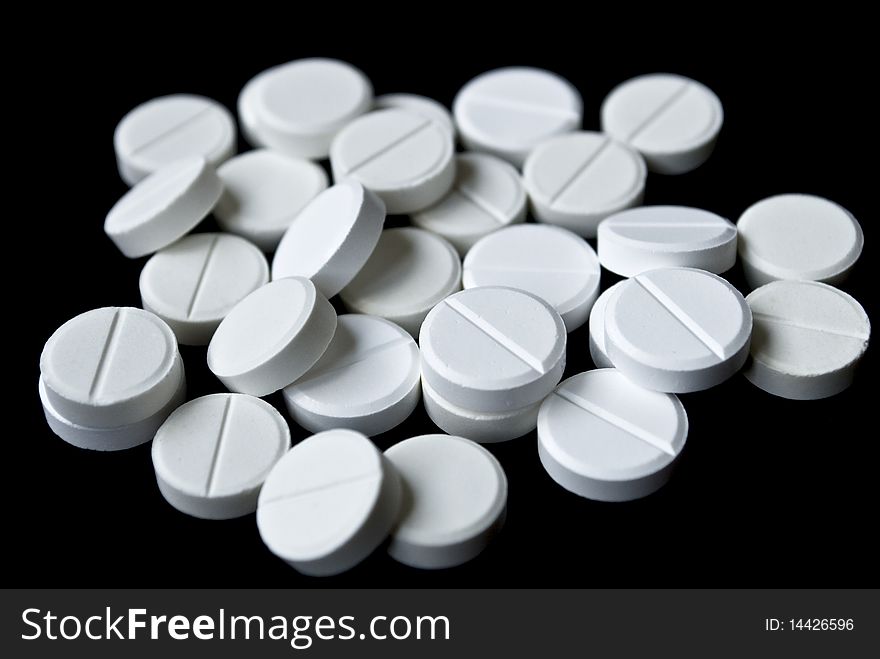 Scattering of white tablets on black background