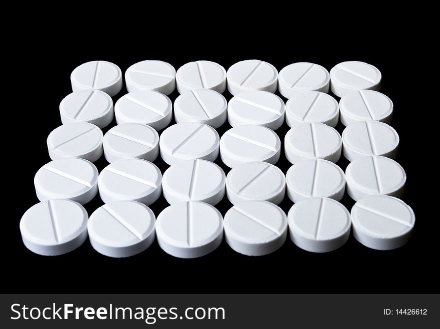 White pills arranged on the black background