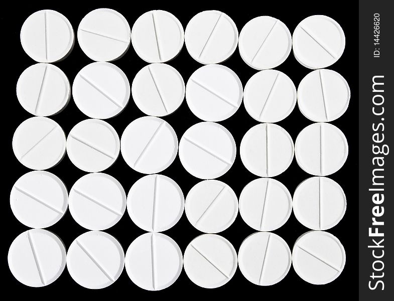 White pills arranged on the black background