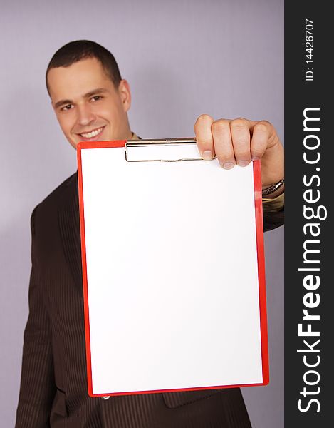 Young businessman showing a blank paper. There you can write a text. Young businessman showing a blank paper. There you can write a text