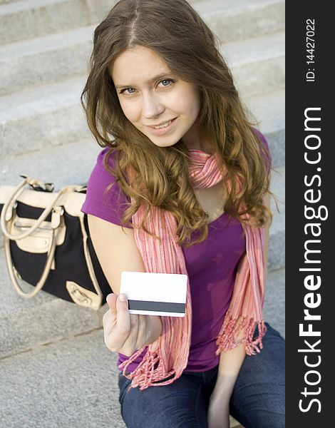 A woman holds in her hand a plastic card for purchases
