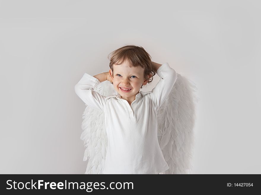 Beautiful little angel boy, white clothes, wings, blue eyes