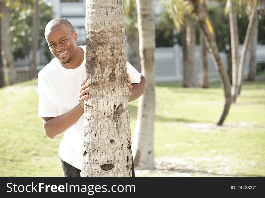 Man Smiling From Behind A Tree