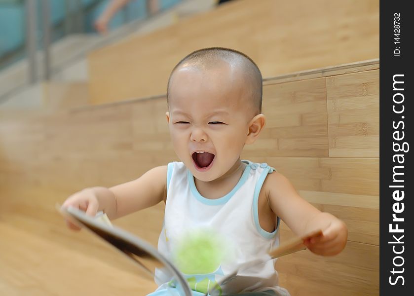 A Chinese baby is reading a book. He is very happy. A Chinese baby is reading a book. He is very happy.