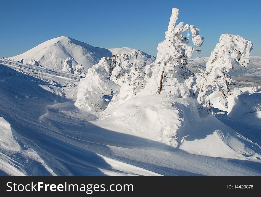A winter landscape with white mountain top and a snow slope. A winter landscape with white mountain top and a snow slope.
