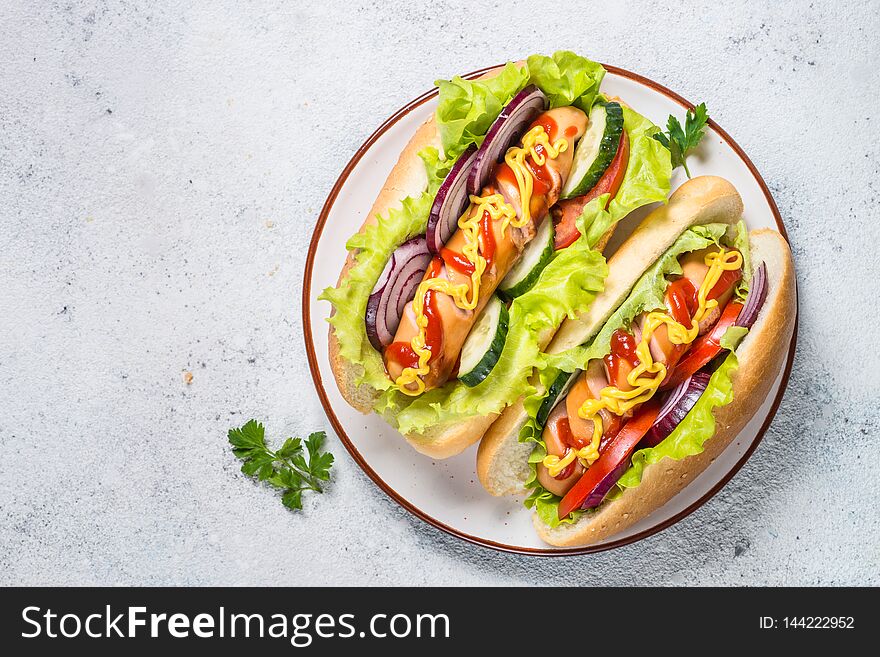Hot dog with fresh vegetables in white plate on white table. Top view with copy space. Hot dog with fresh vegetables in white plate on white table. Top view with copy space.
